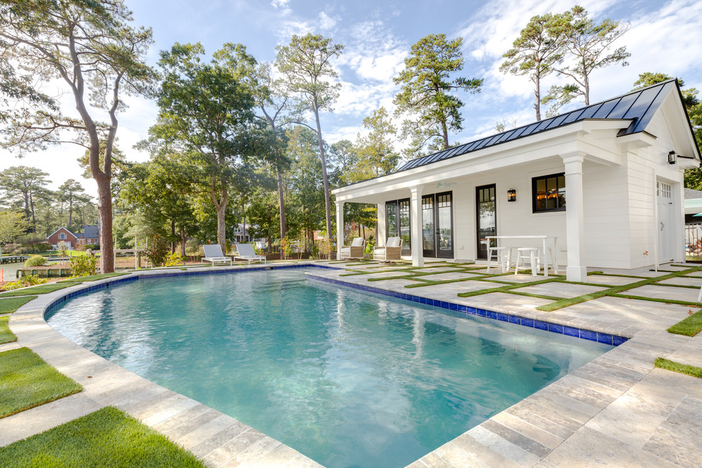 Photo of a large modern back custom shaped natural swimming pool in Other with a pool house and natural stone paving.