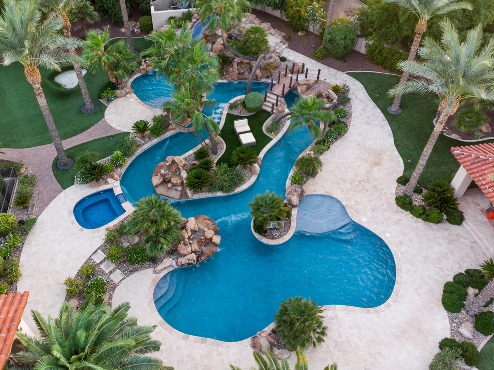 Inspiration for a large world-inspired back custom shaped swimming pool in Phoenix with a water slide and natural stone paving.