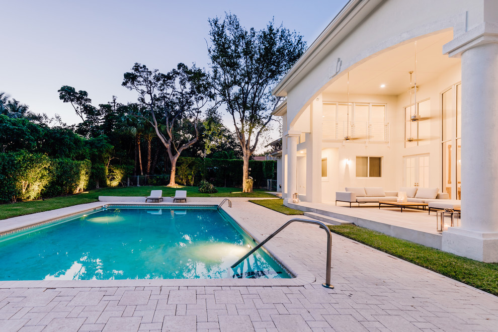 Imagen de piscina alargada contemporánea rectangular en patio trasero con adoquines de ladrillo