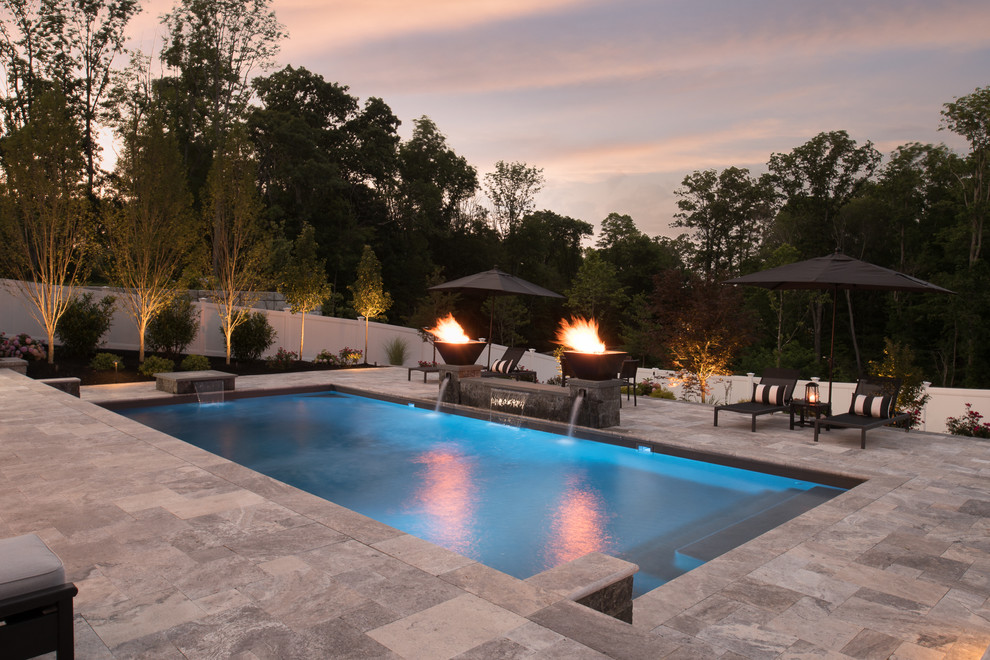 Ejemplo de piscina con fuente alargada clásica grande rectangular en patio trasero con suelo de baldosas