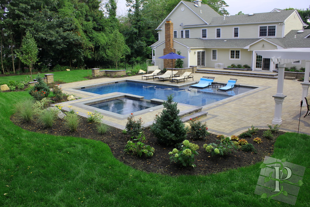 Modelo de piscinas y jacuzzis actuales grandes rectangulares en patio trasero con adoquines de hormigón