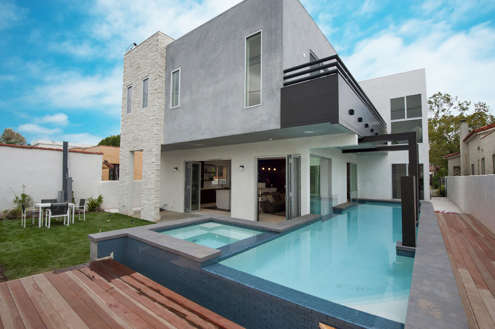 Ispirazione per una piscina fuori terra design a "L" di medie dimensioni e dietro casa con una vasca idromassaggio e pedane