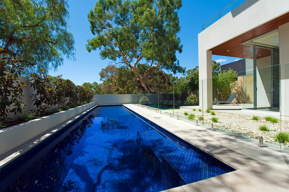 Foto di una grande piscina monocorsia moderna rettangolare dietro casa con pavimentazioni in pietra naturale
