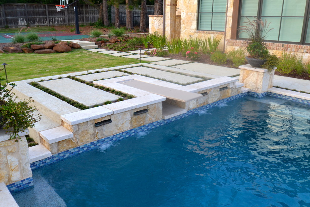 Exempel på en stor modern pool på baksidan av huset, med en fontän och naturstensplattor