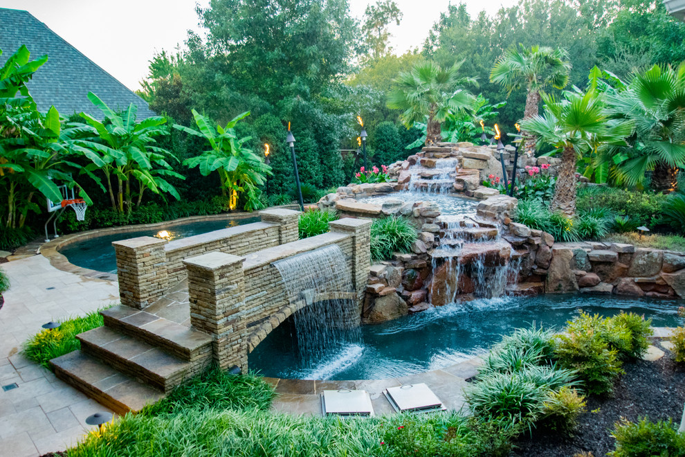 Foto de piscina con fuente tropical grande a medida en patio trasero con adoquines de piedra natural
