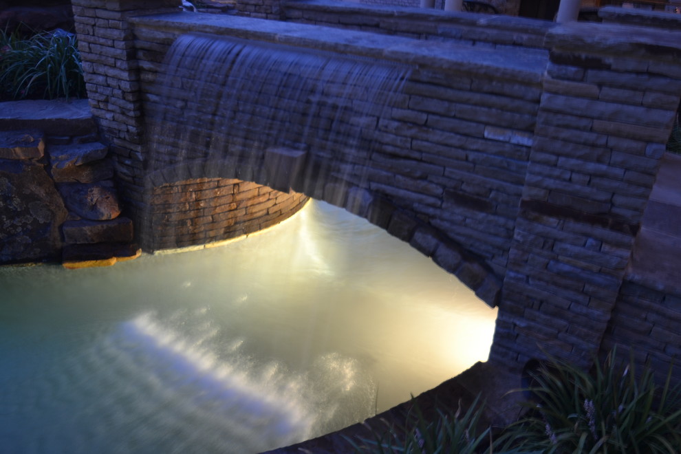 Modelo de piscina con fuente natural exótica grande a medida en patio trasero con adoquines de piedra natural