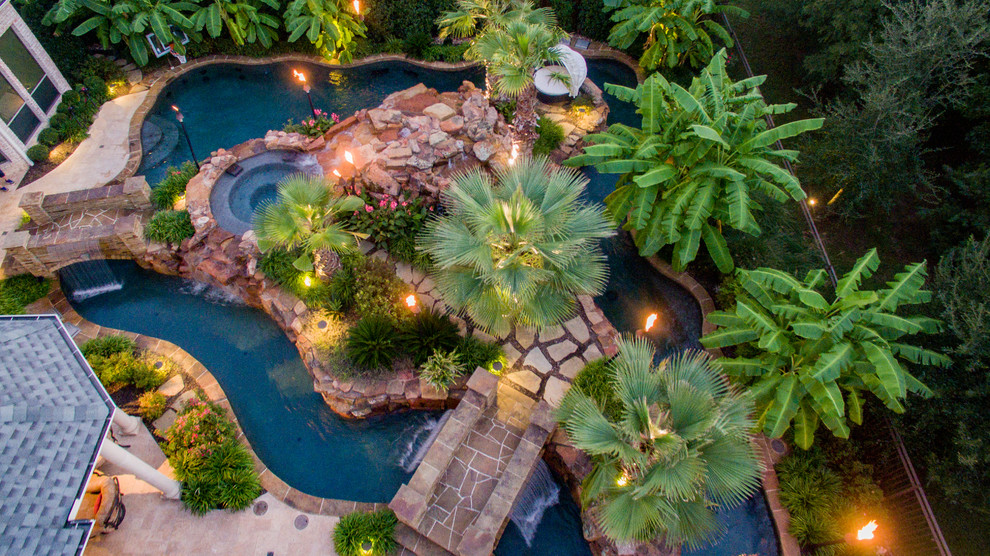 Imagen de piscina con fuente exótica grande a medida en patio trasero con adoquines de piedra natural