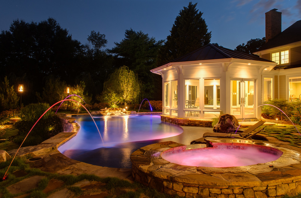 Идея дизайна: большой бассейн-инфинити произвольной формы на заднем дворе в классическом стиле с джакузи и покрытием из каменной брусчатки
