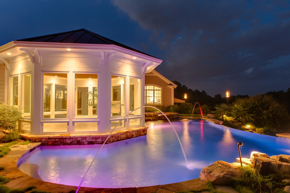 Esempio di una piscina a sfioro infinito classica personalizzata di medie dimensioni e dietro casa con una vasca idromassaggio e pavimentazioni in pietra naturale