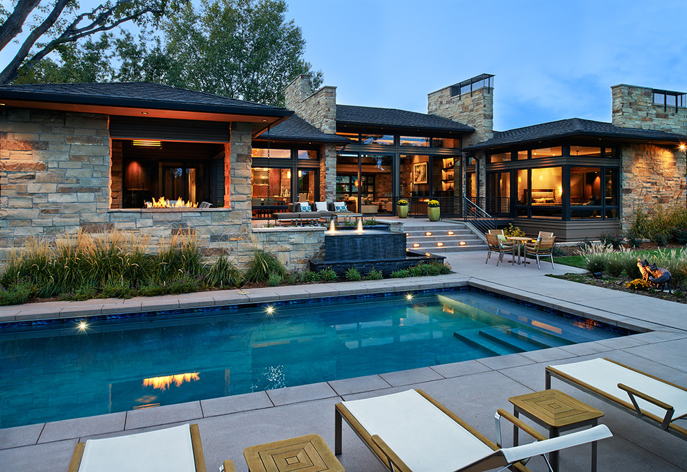 Diseño de piscina con fuente alargada contemporánea grande rectangular en patio trasero con losas de hormigón