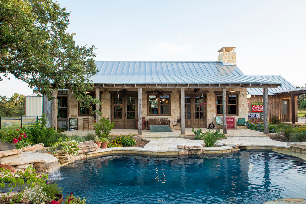 Inspiration for a medium sized rustic back custom shaped swimming pool in Austin with a pool house and natural stone paving.