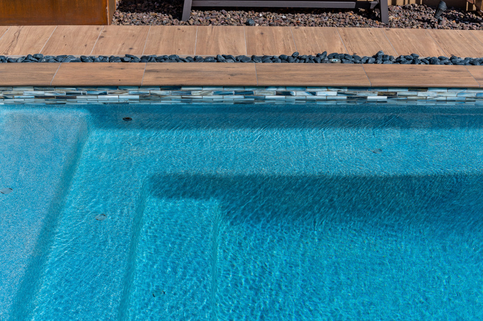 Modelo de piscina pequeña rectangular en patio trasero con suelo de baldosas