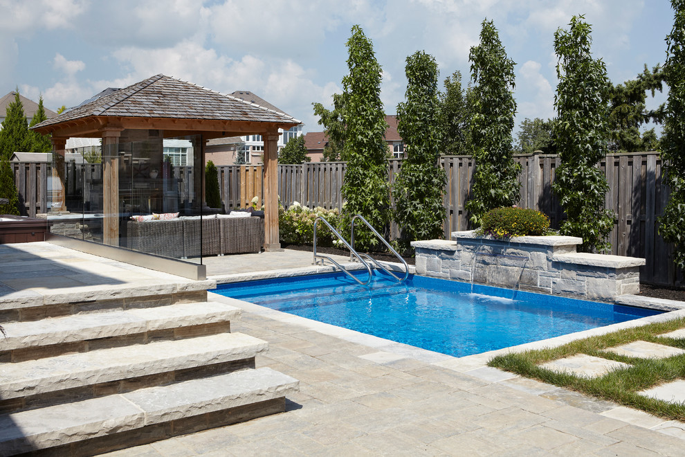 Imagen de piscina con fuente natural actual pequeña rectangular en patio trasero con adoquines de ladrillo
