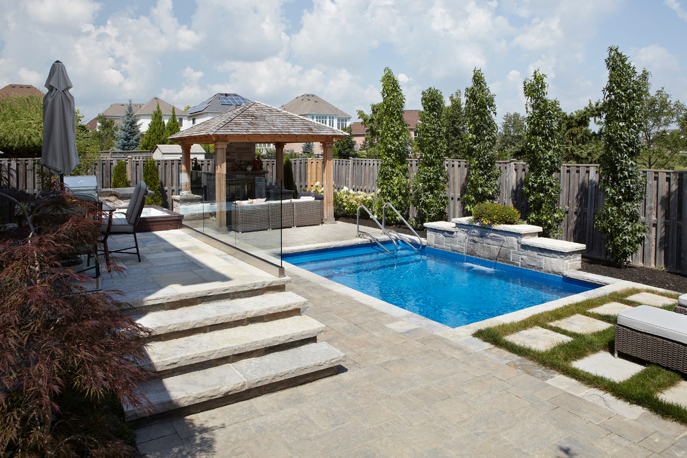 Diseño de piscina con fuente natural actual pequeña rectangular en patio trasero con adoquines de ladrillo