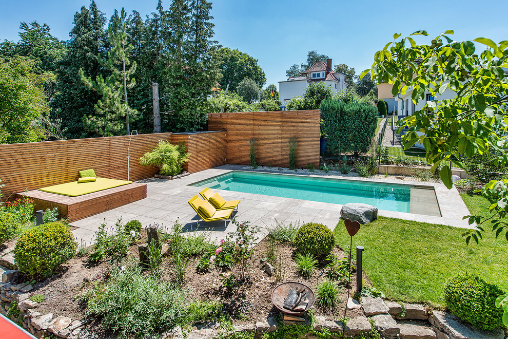 Ispirazione per una piscina monocorsia contemporanea rettangolare dietro casa e di medie dimensioni con pavimentazioni in pietra naturale e fontane