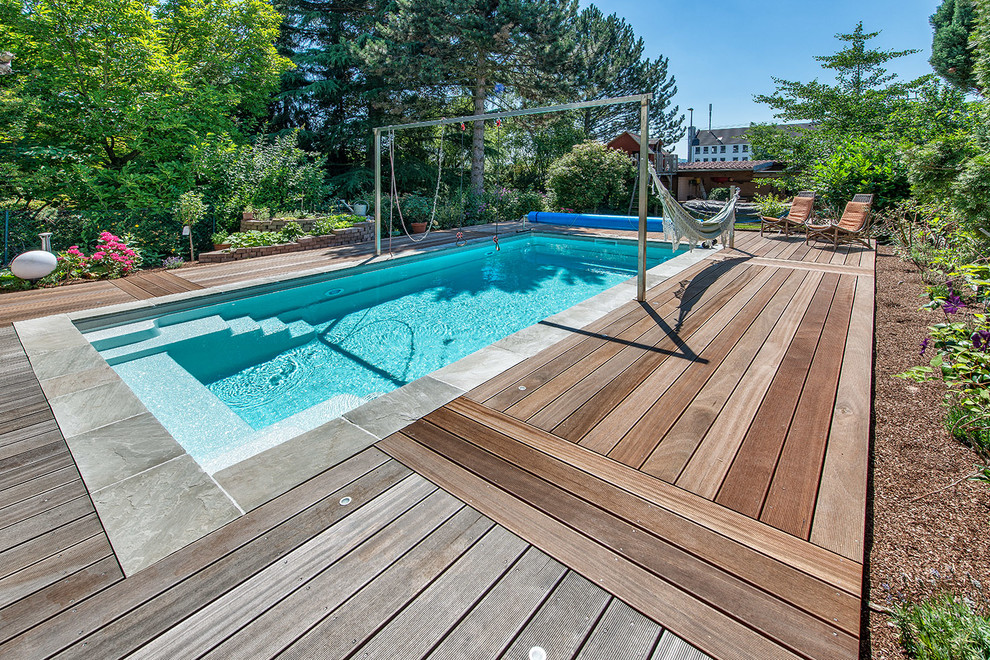Ejemplo de piscina con fuente alargada actual de tamaño medio rectangular en patio trasero con entablado