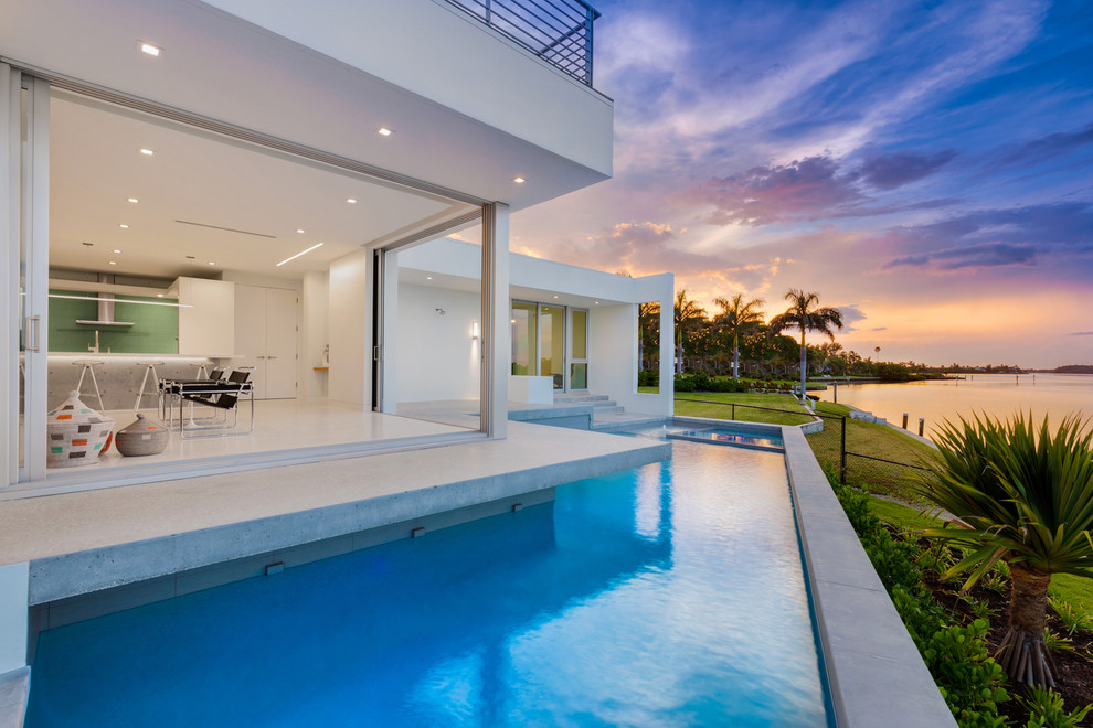 Immagine di una grande piscina minimal personalizzata dietro casa con una vasca idromassaggio e lastre di cemento
