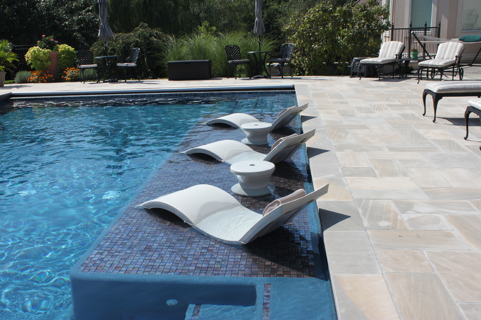 Immagine di una grande piscina mediterranea rettangolare dietro casa con pavimentazioni in pietra naturale