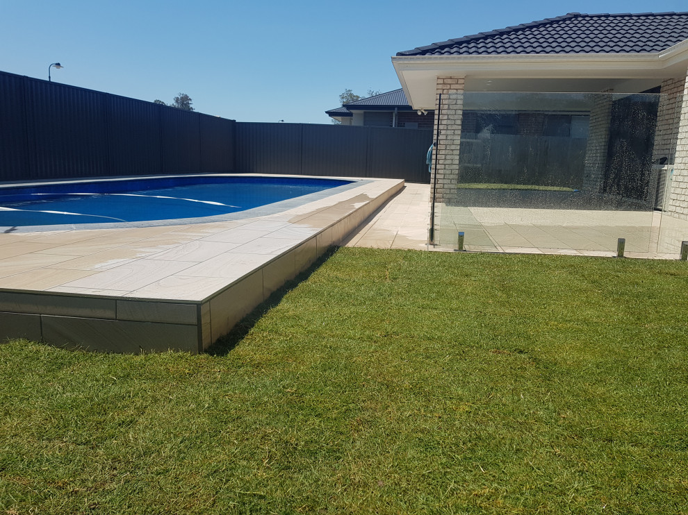 Стильный дизайн: наземный бассейн среднего размера, произвольной формы на заднем дворе в стиле модернизм с домиком у бассейна и покрытием из плитки - последний тренд