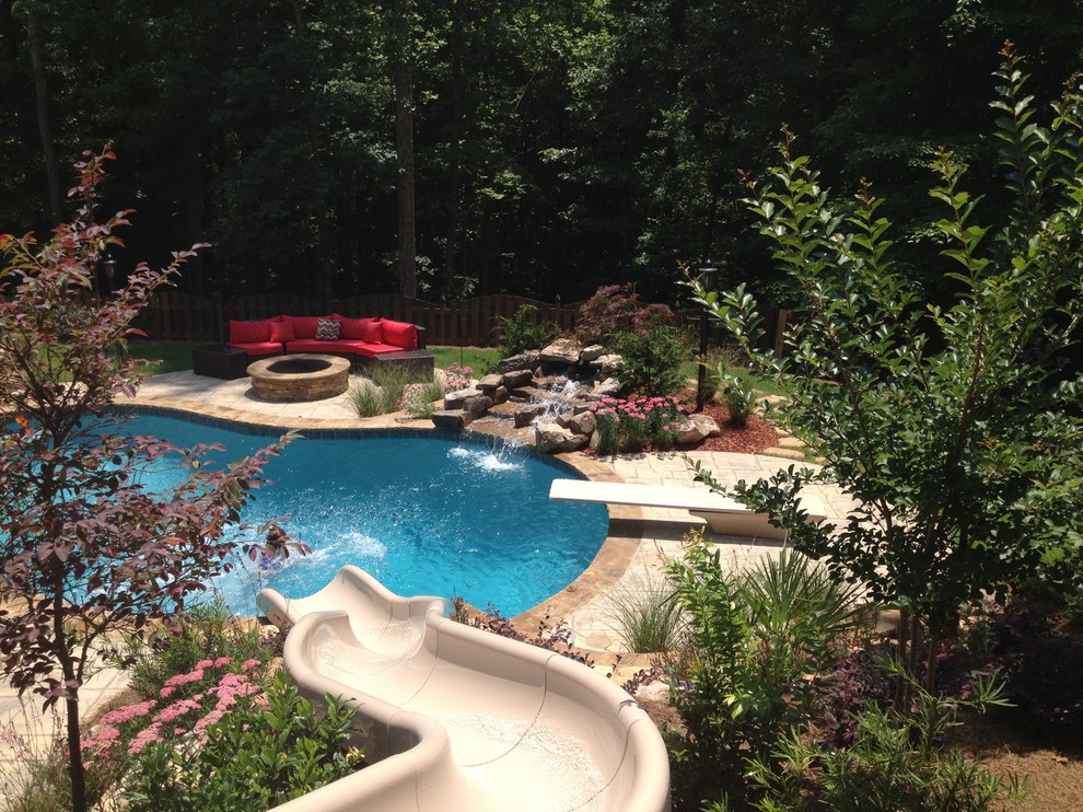 Diseño de piscina con tobogán clásica de tamaño medio a medida en patio trasero con suelo de hormigón estampado