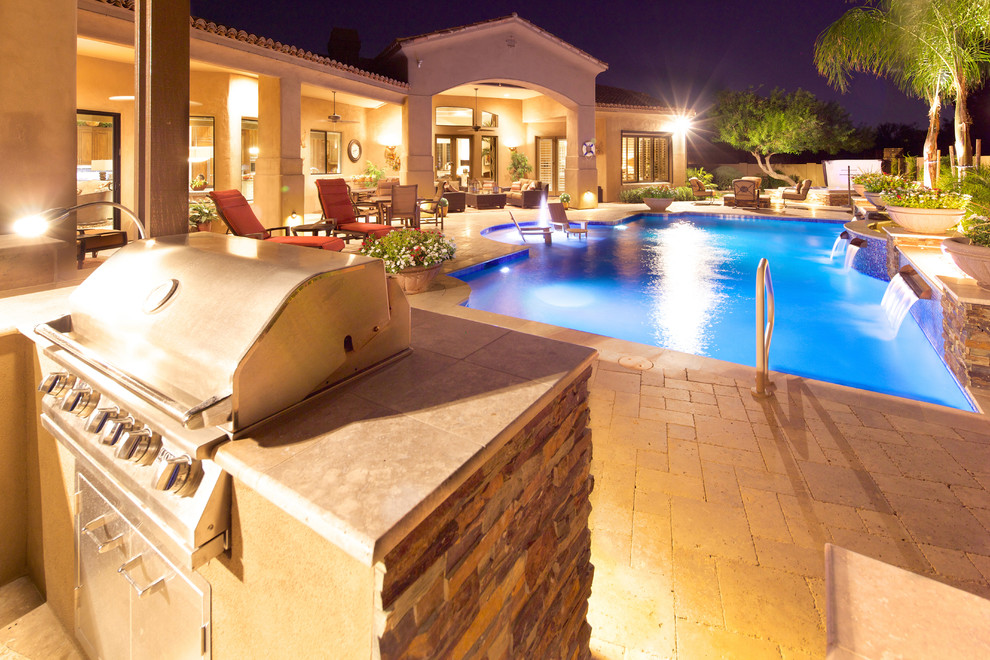 This is an example of a large mediterranean back custom shaped natural swimming pool in Phoenix with natural stone paving.