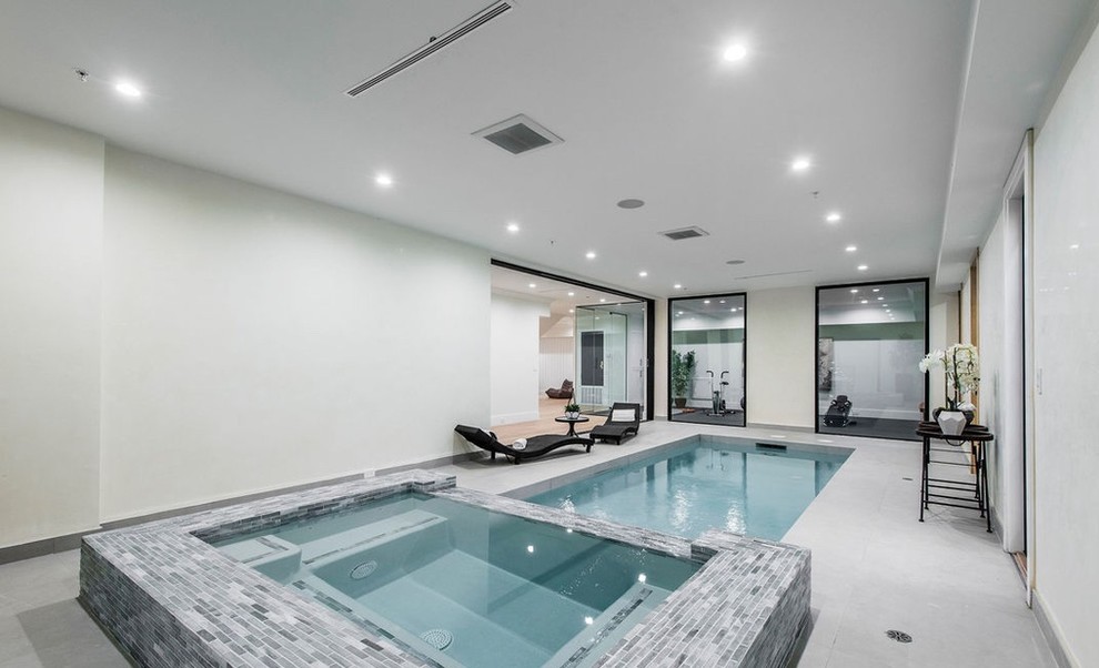 Ispirazione per una piscina coperta monocorsia contemporanea rettangolare di medie dimensioni con una vasca idromassaggio e pavimentazioni in cemento
