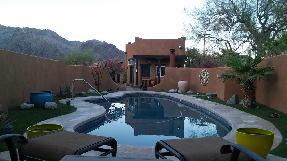 Imagen de piscina natural de estilo americano tipo riñón en patio trasero con adoquines de hormigón