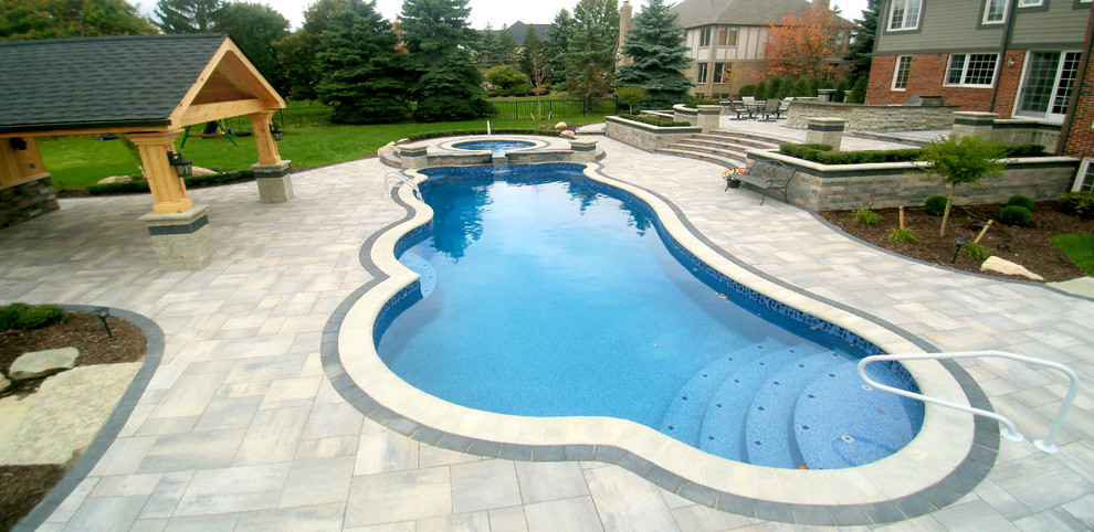 Immagine di un'ampia piscina fuori terra tradizionale personalizzata dietro casa con una vasca idromassaggio e piastrelle