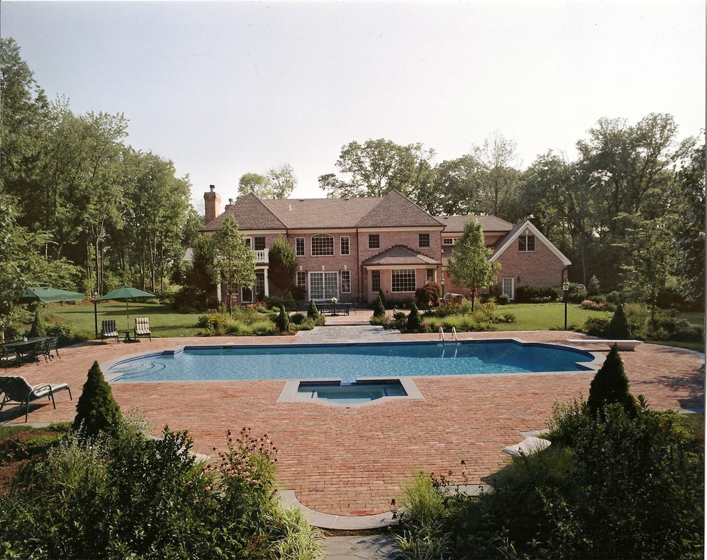На фото: большой спортивный бассейн произвольной формы на заднем дворе в классическом стиле с мощением клинкерной брусчаткой и джакузи с