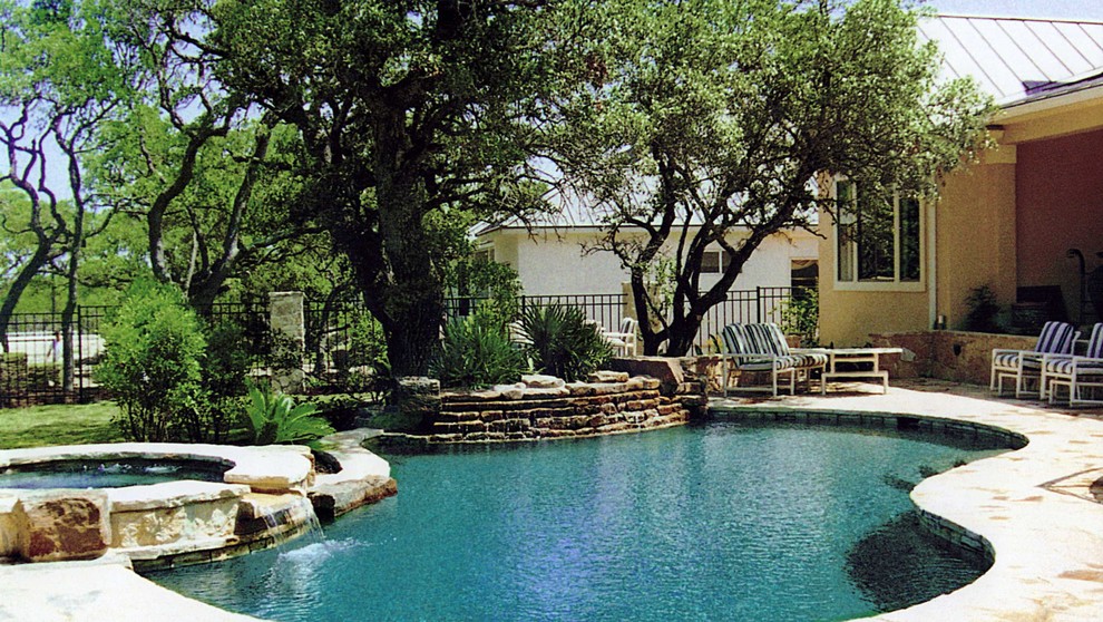 Immagine di una grande piscina classica personalizzata dietro casa con una vasca idromassaggio e pavimentazioni in pietra naturale