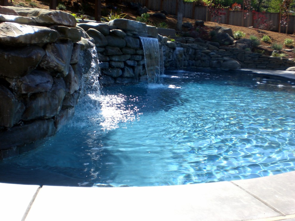 Modelo de piscina con fuente alargada rústica de tamaño medio a medida en patio trasero con adoquines de piedra natural