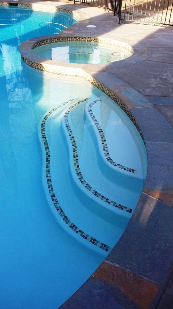 Ispirazione per una grande piscina naturale contemporanea personalizzata dietro casa con una vasca idromassaggio e cemento stampato