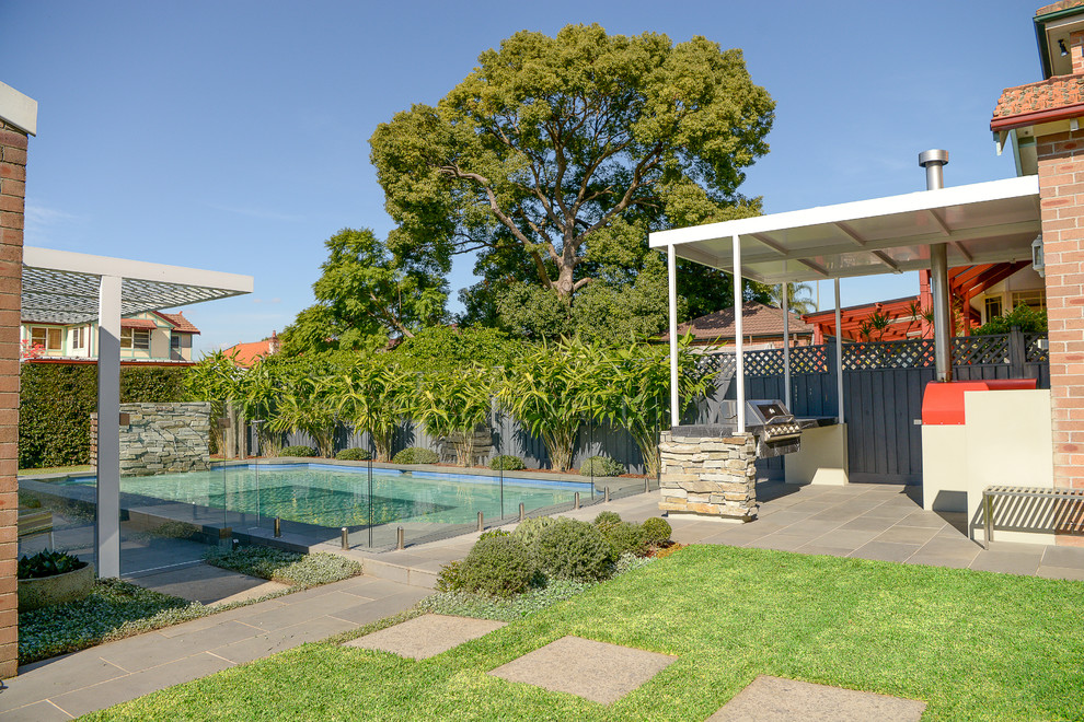 Imagen de piscina con fuente alargada contemporánea de tamaño medio rectangular en patio trasero con adoquines de hormigón