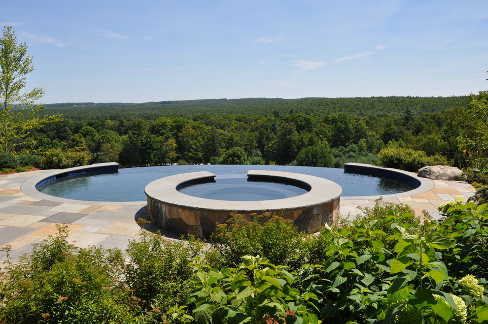 Foto de piscinas y jacuzzis infinitos de estilo americano grandes redondeados en patio trasero con adoquines de piedra natural