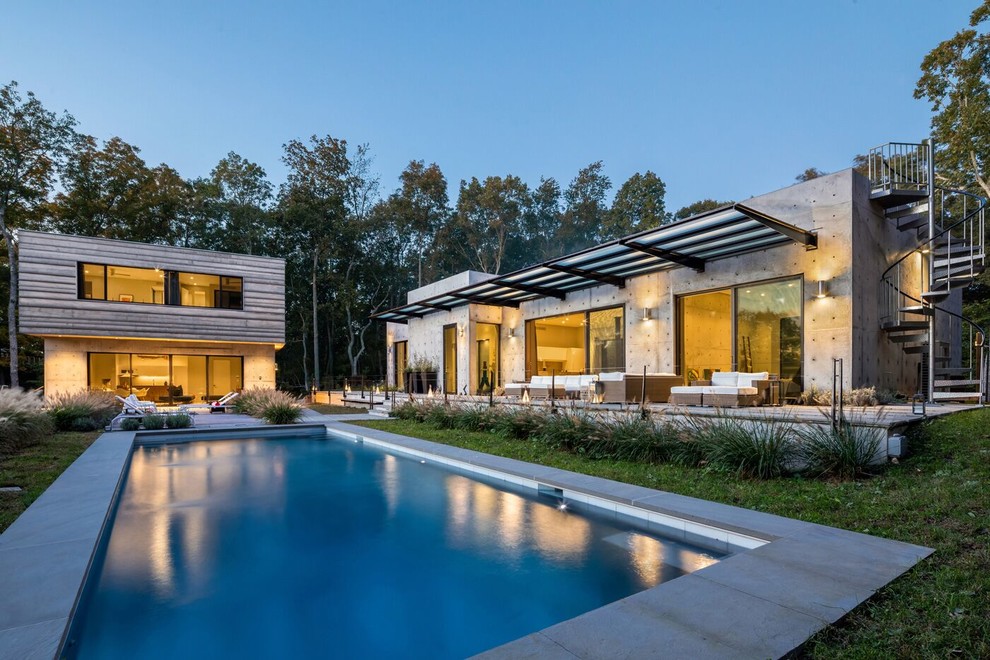 Ejemplo de casa de la piscina y piscina alargada contemporánea grande rectangular en patio delantero con losas de hormigón