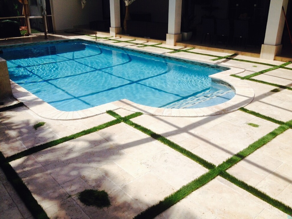 Large traditional back custom shaped lengths swimming pool in Miami with stamped concrete.