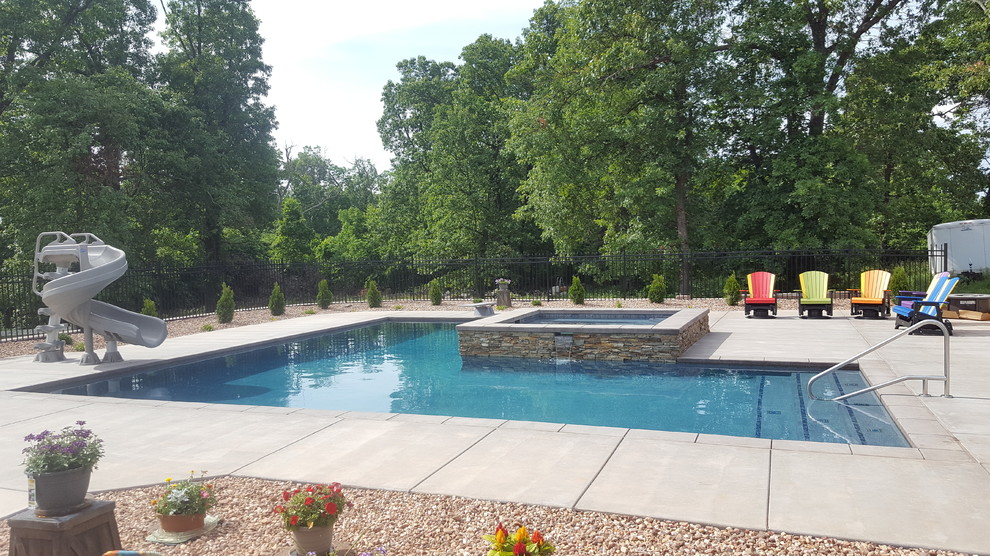 Immagine di un'ampia piscina tradizionale a "L" dietro casa con lastre di cemento