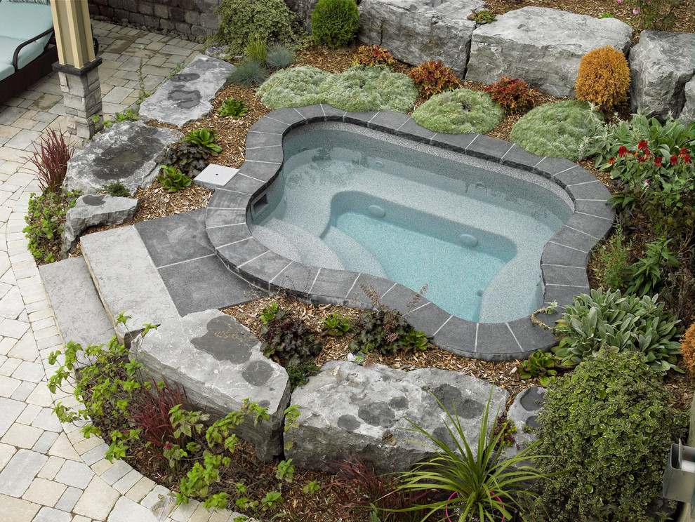 Modelo de piscina con fuente alargada contemporánea de tamaño medio a medida en patio trasero con adoquines de hormigón