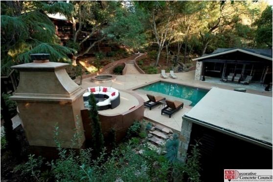 Modelo de piscina tradicional de tamaño medio rectangular en patio trasero con suelo de hormigón estampado
