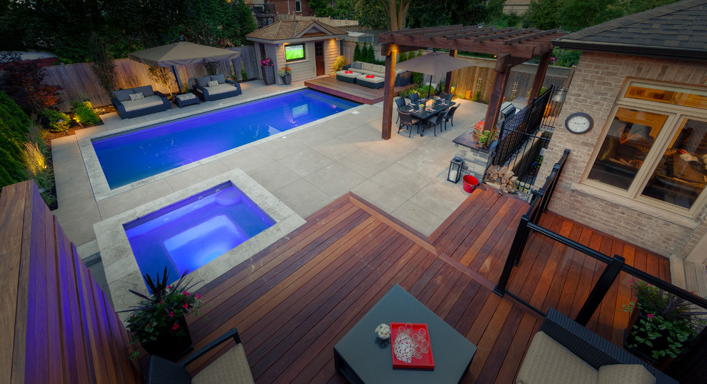 На фото: большой спортивный, прямоугольный бассейн на заднем дворе в современном стиле с джакузи и мощением тротуарной плиткой