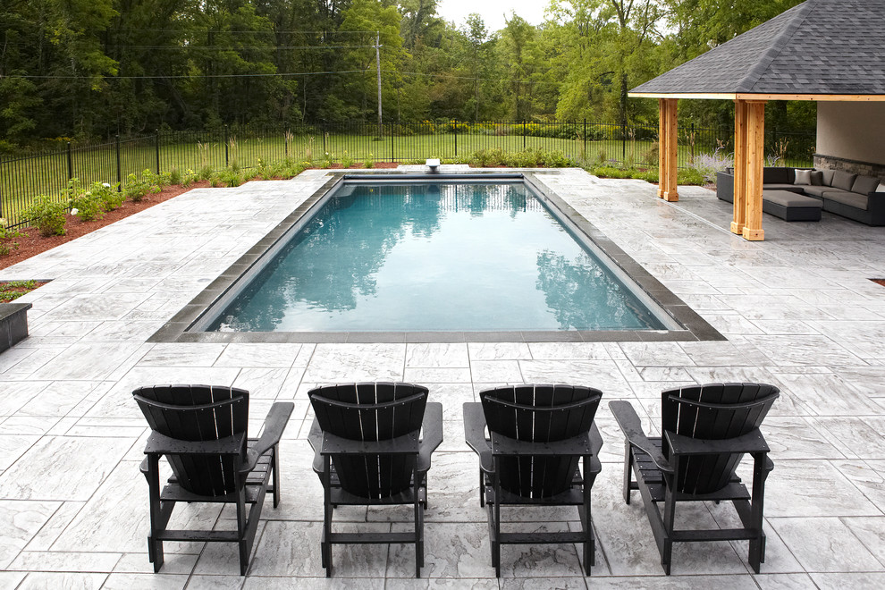 Foto di una piscina monocorsia chic rettangolare di medie dimensioni e dietro casa con una vasca idromassaggio e pavimentazioni in cemento