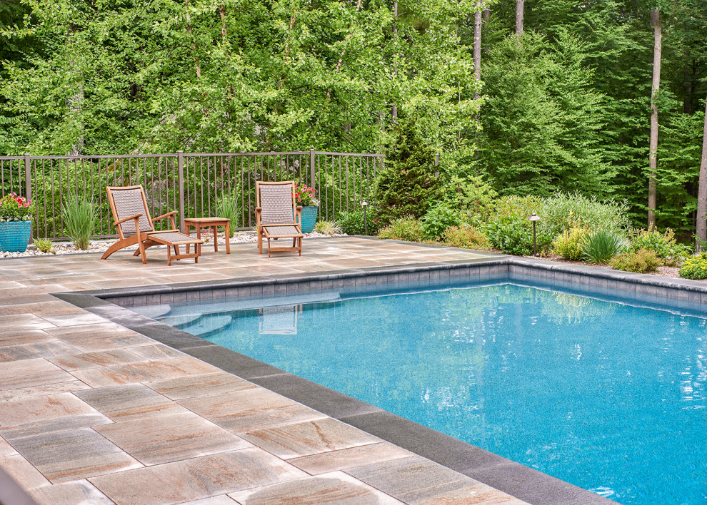 Medium sized traditional side rectangular infinity swimming pool in Boston with with pool landscaping and natural stone paving.