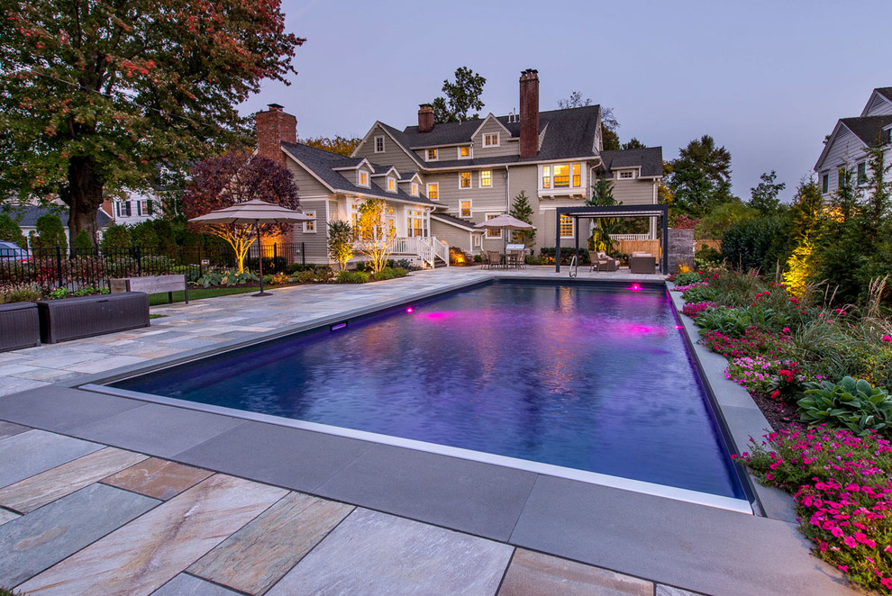 Diseño de piscina actual de tamaño medio en patio trasero con adoquines de piedra natural
