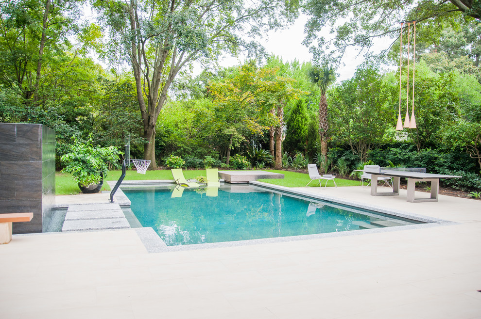 Esempio di una grande piscina naturale minimal rettangolare dietro casa con fontane e pavimentazioni in cemento
