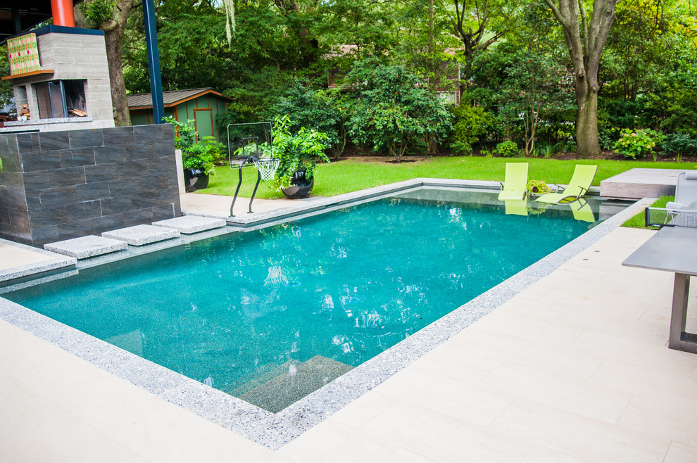 Ispirazione per una grande piscina naturale design rettangolare dietro casa con fontane e pavimentazioni in cemento
