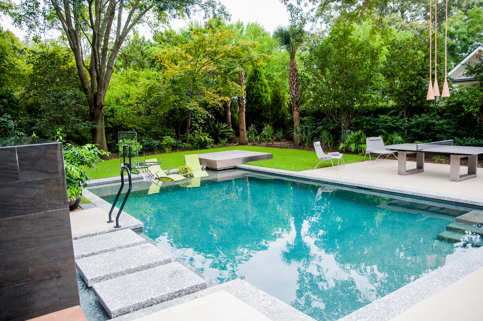 Diseño de piscina con fuente natural actual grande rectangular en patio trasero con adoquines de hormigón