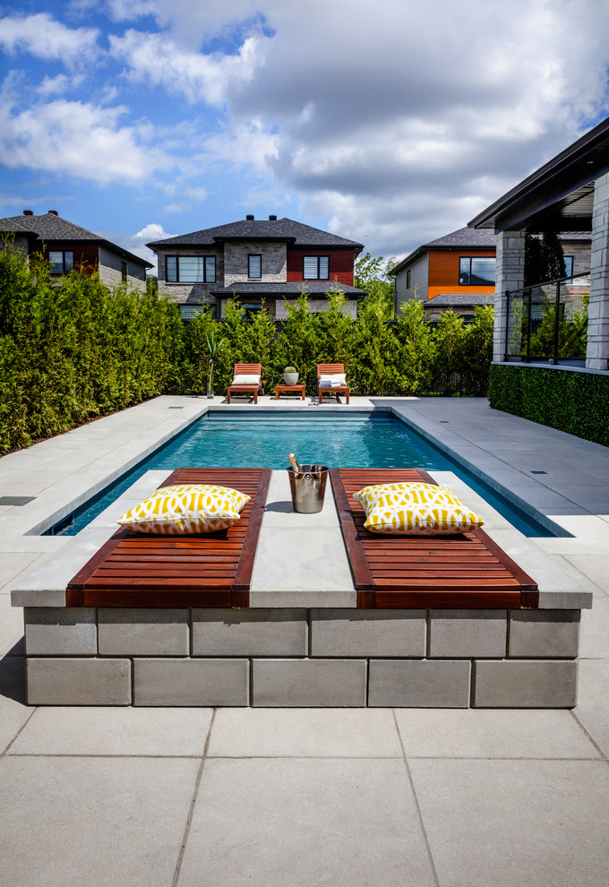 Ejemplo de piscina alargada actual rectangular en patio trasero con adoquines de hormigón