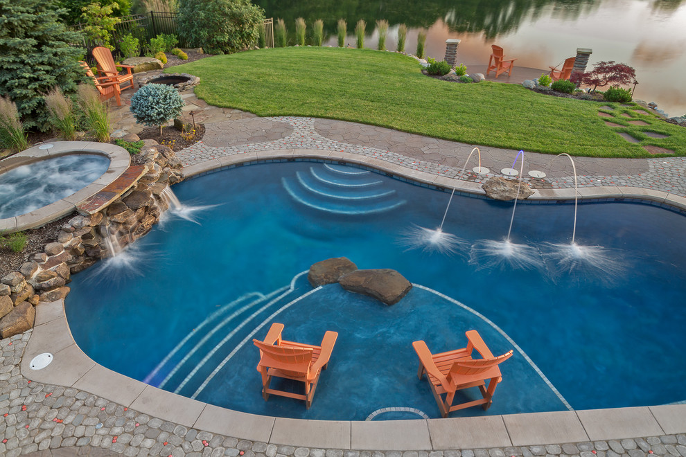Immagine di una grande piscina monocorsia contemporanea a "C" dietro casa con cemento stampato e fontane