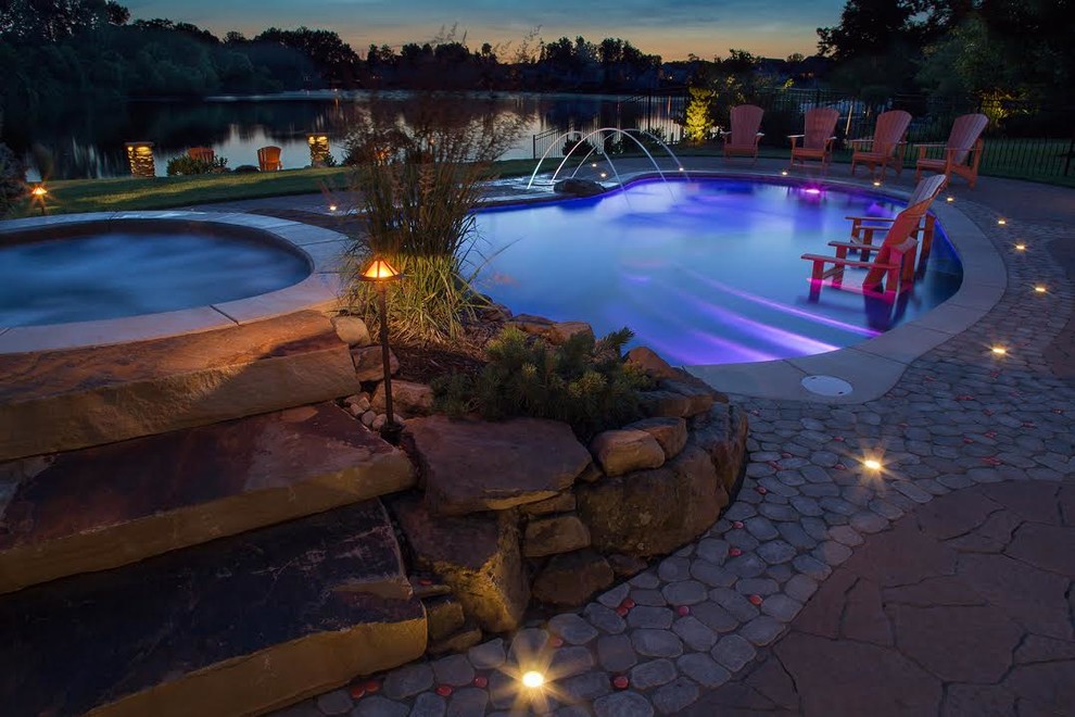 Large contemporary back kidney-shaped lengths swimming pool in Cleveland with stamped concrete and a water feature.