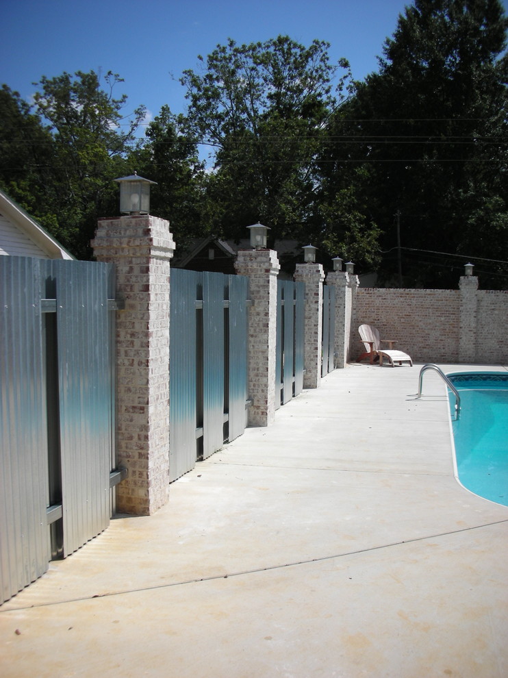 Imagen de piscina alargada actual de tamaño medio redondeada en patio trasero con losas de hormigón